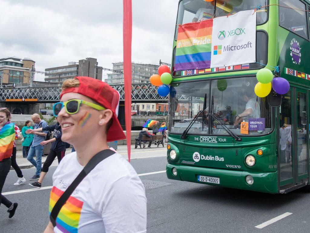 A Picture of a Dublin Bus and people taking part in the Dublin Pride Parade
