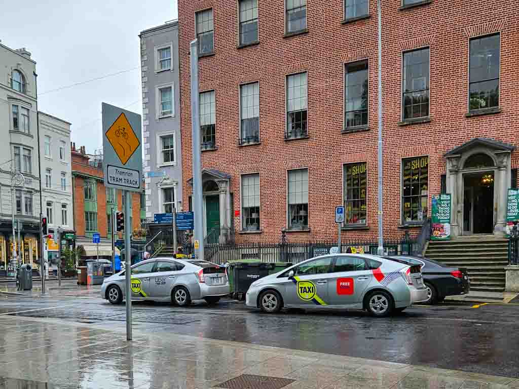 A picture of two Dublin taxis stopped on St Stephen's Green on a wet day in the city.