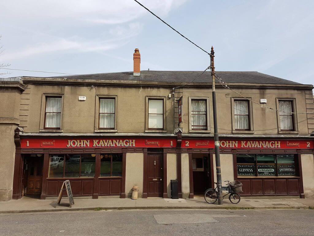A picture of the exterior of John Kavanagh Gravediggers pub in Dublin with its wine coloured wooden paneling and red sign across the front.