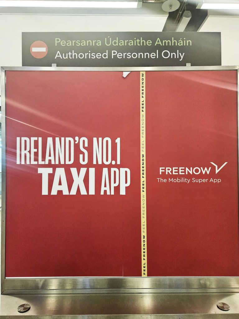 A picture of the red FREENOW Taxi App advertisement in Dublin Airport.