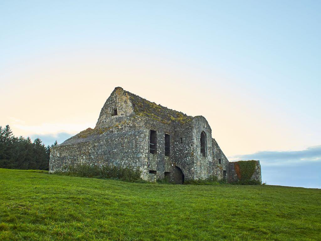 A picture of the ruined Hellfire Club in the Dublin Mountains with a blue sky overhead and green grass surrounding it.