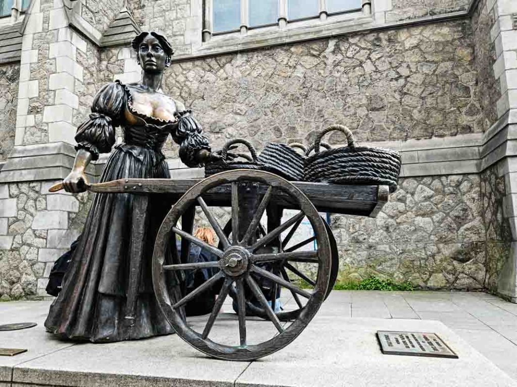 A picture of the Molly Malone statue, located on Suffolk Street in Dublin. she standing in her dress, wheeling her wheelbarrow full of cockles and mussels to sell.