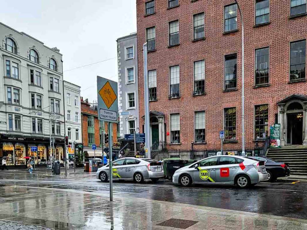 A picture of two Dublin taxis on St Stephen's Green outside the Little Museum of Dublin on a rainy day.